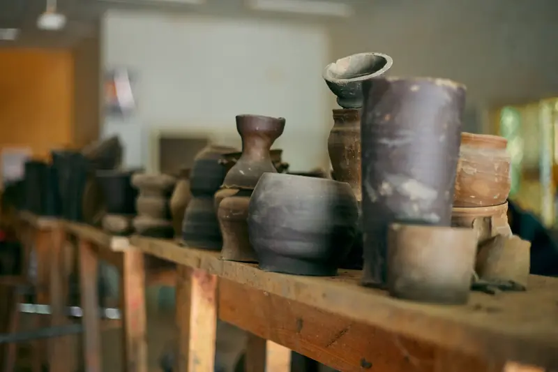 A collection of rustic pottery displayed on a wooden shelf, capturing the artisanal charm of handmade ceramics