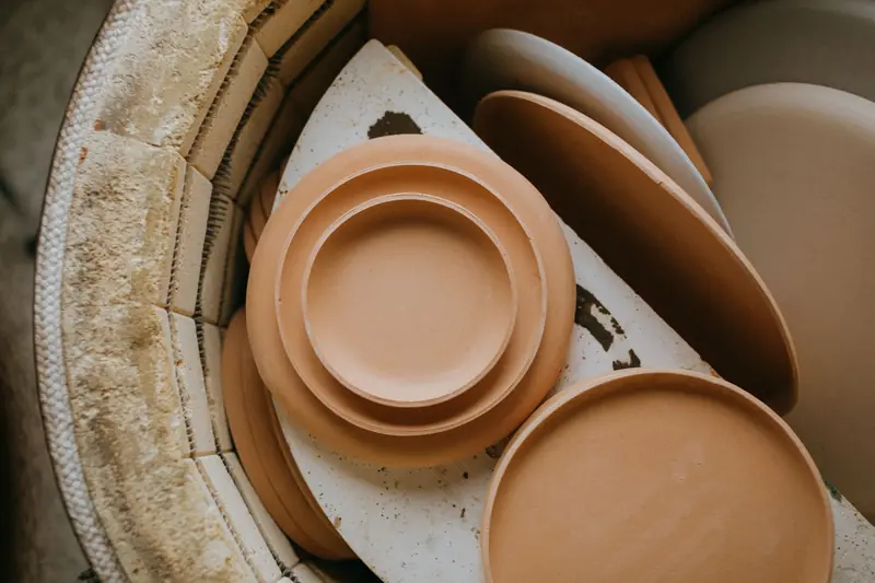 Warm-toned ceramic plates stacked inside a kiln, ready for firing