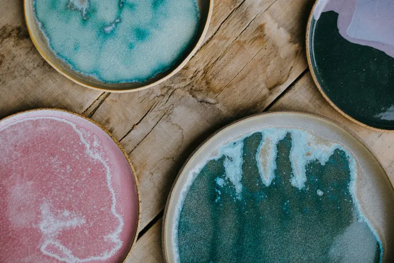 Overhead view of colorful ceramic plates with artistic glaze patterns on a rustic wooden table