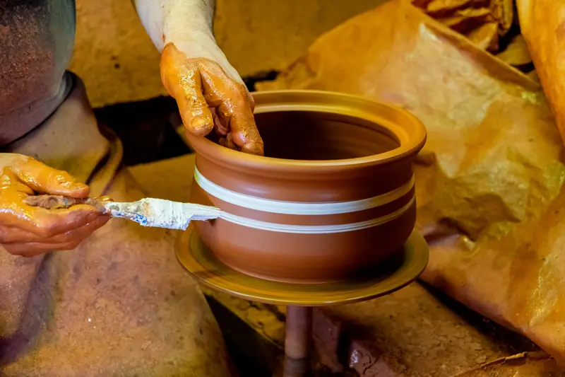 Hands shaping a clay pot on a pottery wheel, highlighting traditional craftsmanship and skill