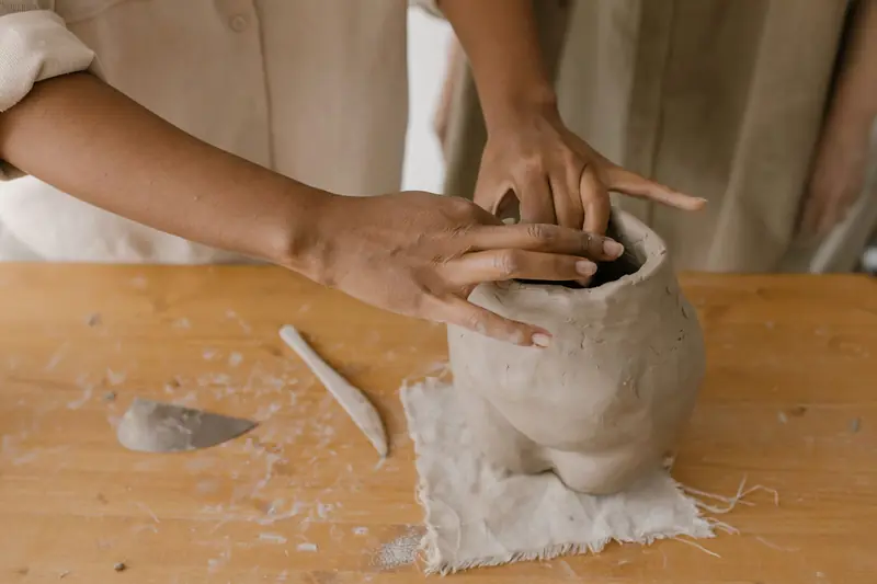 Close-up view of hands molding a clay pot, showcasing pottery techniques and craftsmanship