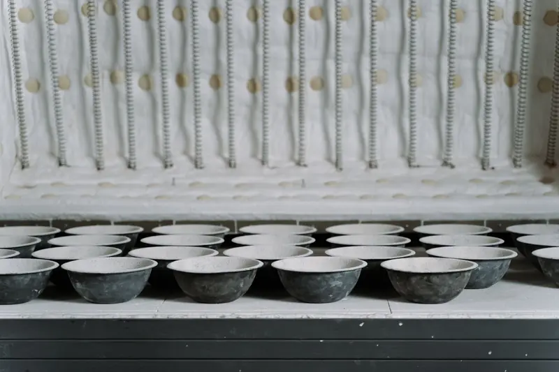 A collection of ceramic bowls arranged inside an open kiln for firing in a pottery workshop