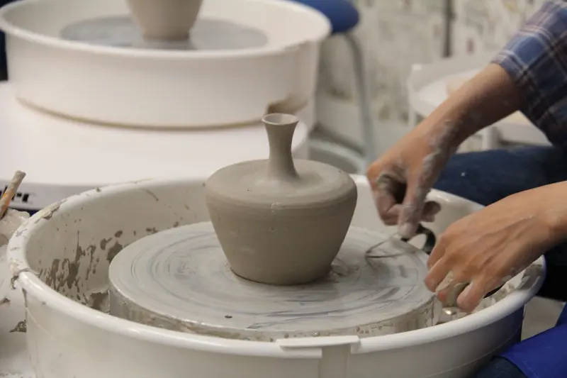 Close-up of hands skillfully shaping clay pottery on a wheel in a creative studio setting