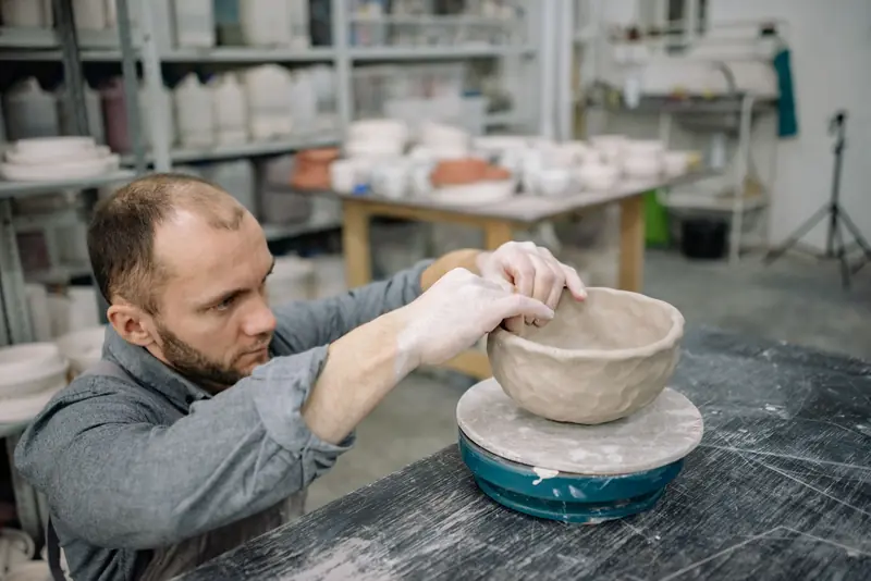 Man skillfully shaping a clay bowl in an artisan pottery studio workshop