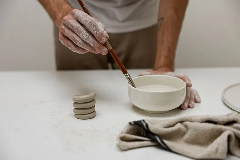 Close-up of an artist painting a ceramic bowl with precise handwork and craftsmanship