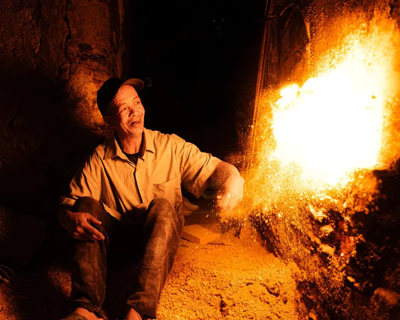 Man working in a glowing kiln in Marrakech, capturing the intense heat and rustic environment