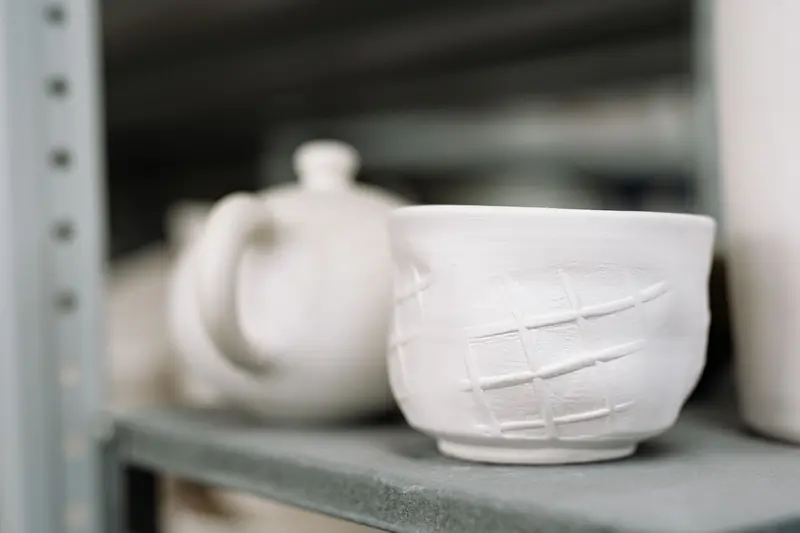 White handmade clay pottery with unique textures displayed on shelves