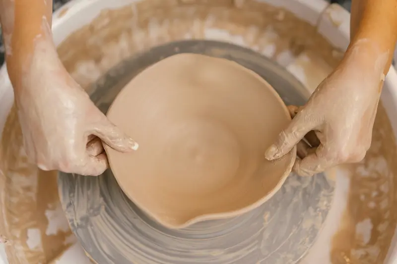 Close-up of hands shaping a ceramic bowl on a pottery wheel, showcasing craftsmanship