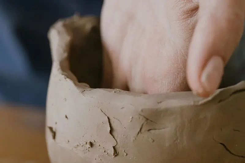 Artisan hand shaping a clay pot, highlighting craftsmanship and creativity in a pottery studio