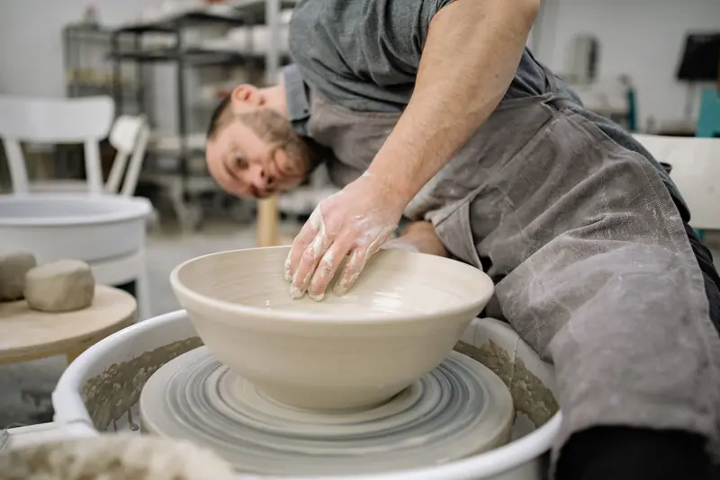 Skilled potter shaping clay on a pottery wheel in an artisan studio, showcasing craftsmanship and focus
