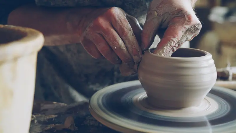 Artisan skillfully shapes clay on a spinning wheel, showcasing traditional pottery techniques